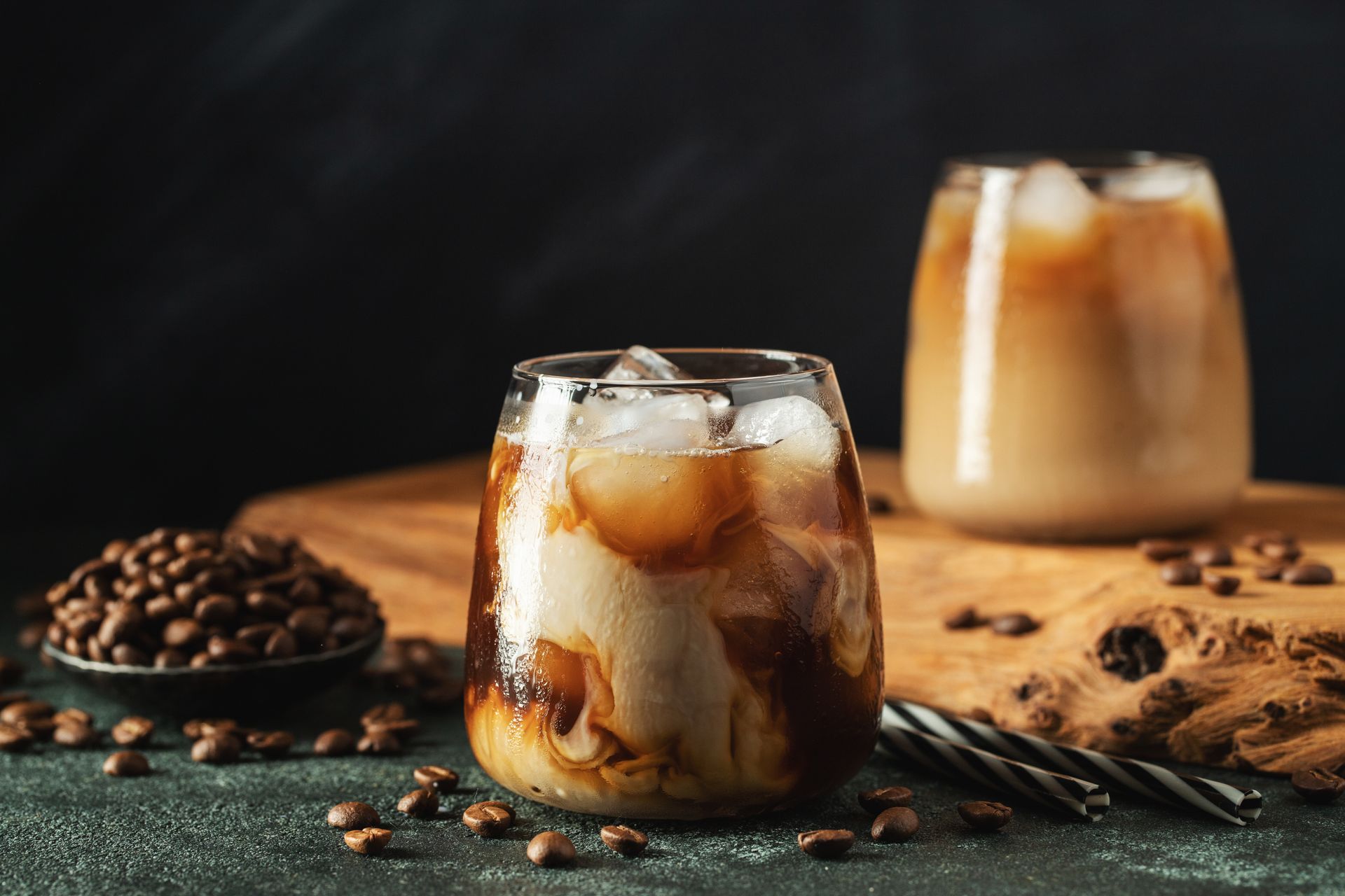 Two glasses of iced coffee with ice and milk on a table.