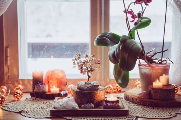 A window sill with candles , crystals , and a potted plant.