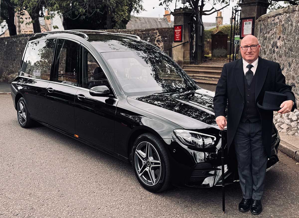 Barry Whalen walking in front of the cars