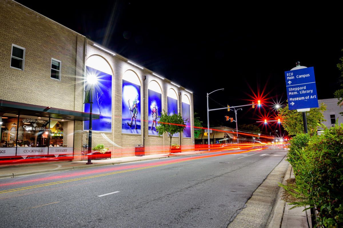 A long exposure photo of a street at night with a building in the background.