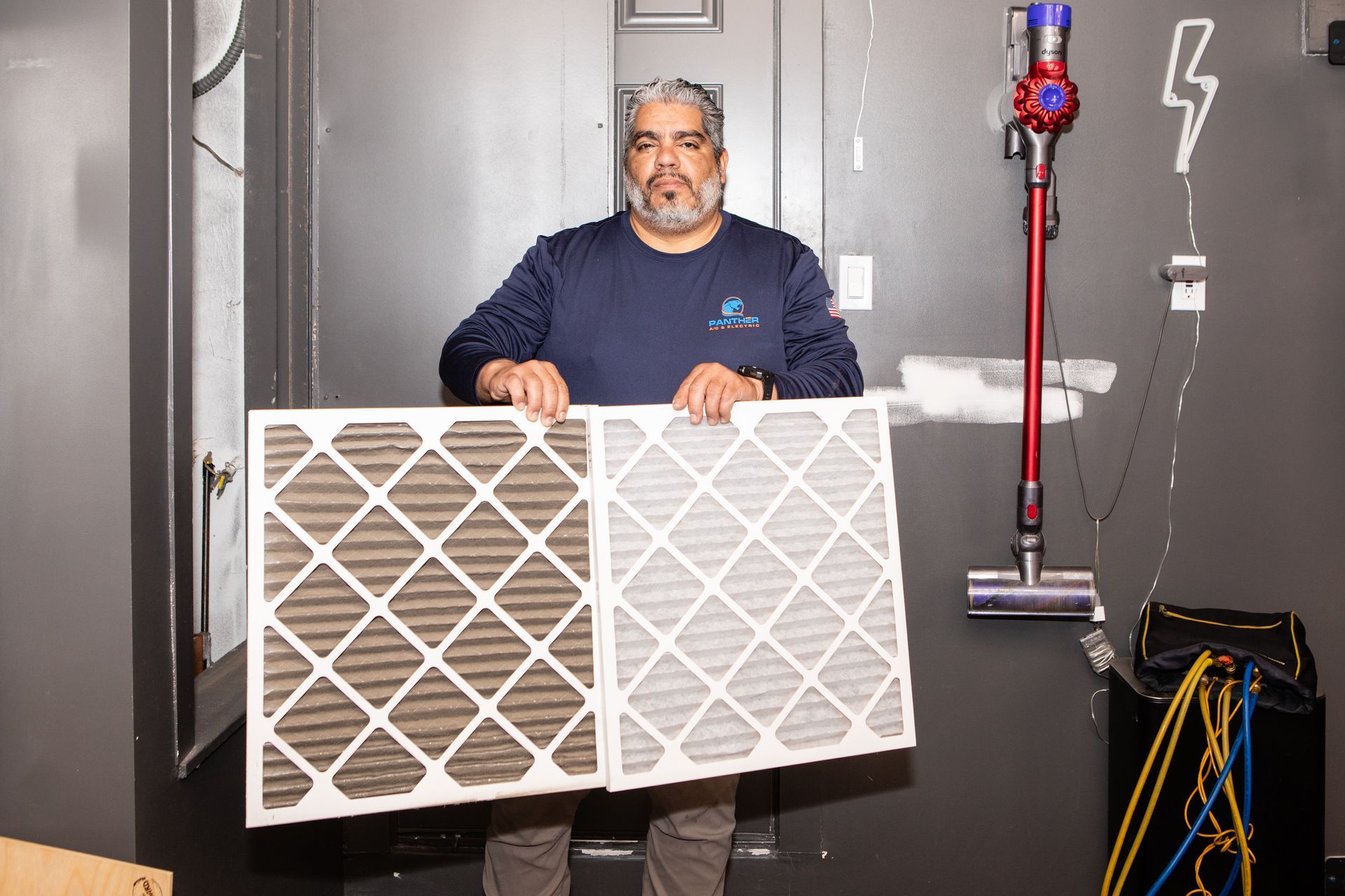 A man is cleaning an air filter on a wall.