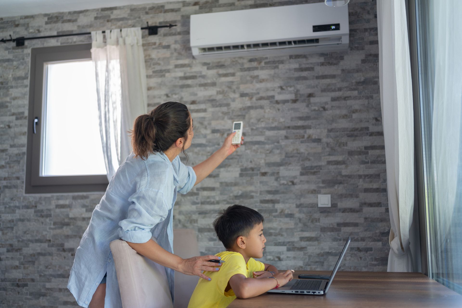 Mother adjusting AC unit ahead of hurricane season in Miami, Florida.