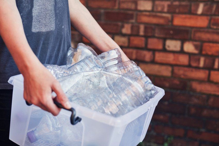 Woman working in a recycling factory sorting some bottles and looking very happy - environmental concepts