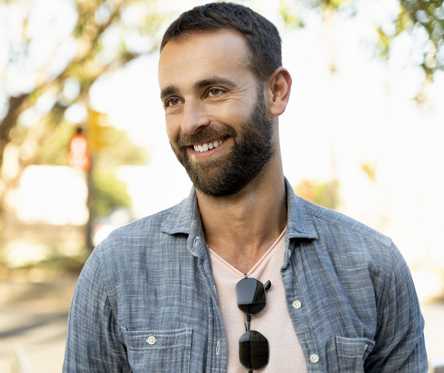 A man with a beard is smiling and wearing sunglasses.