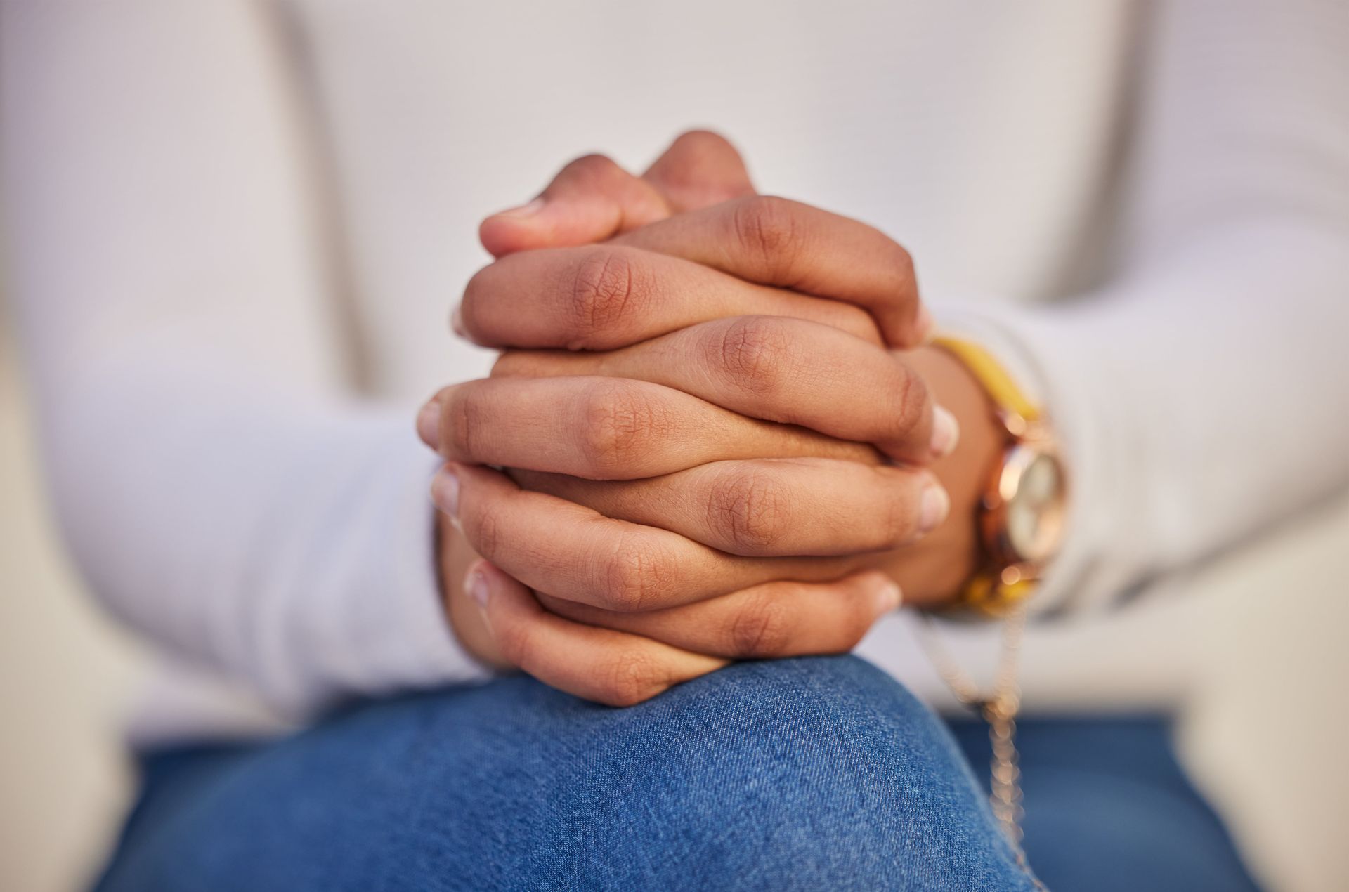 A person is sitting with their hands folded in prayer.