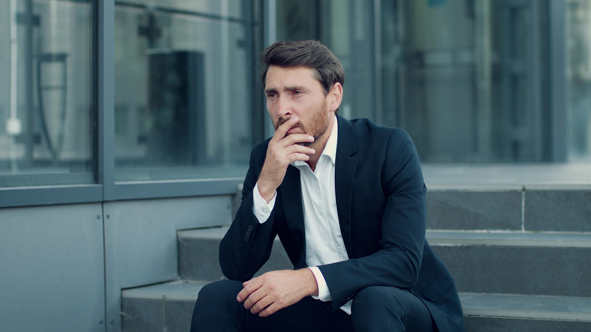 A man in a suit is sitting on the steps of a building.