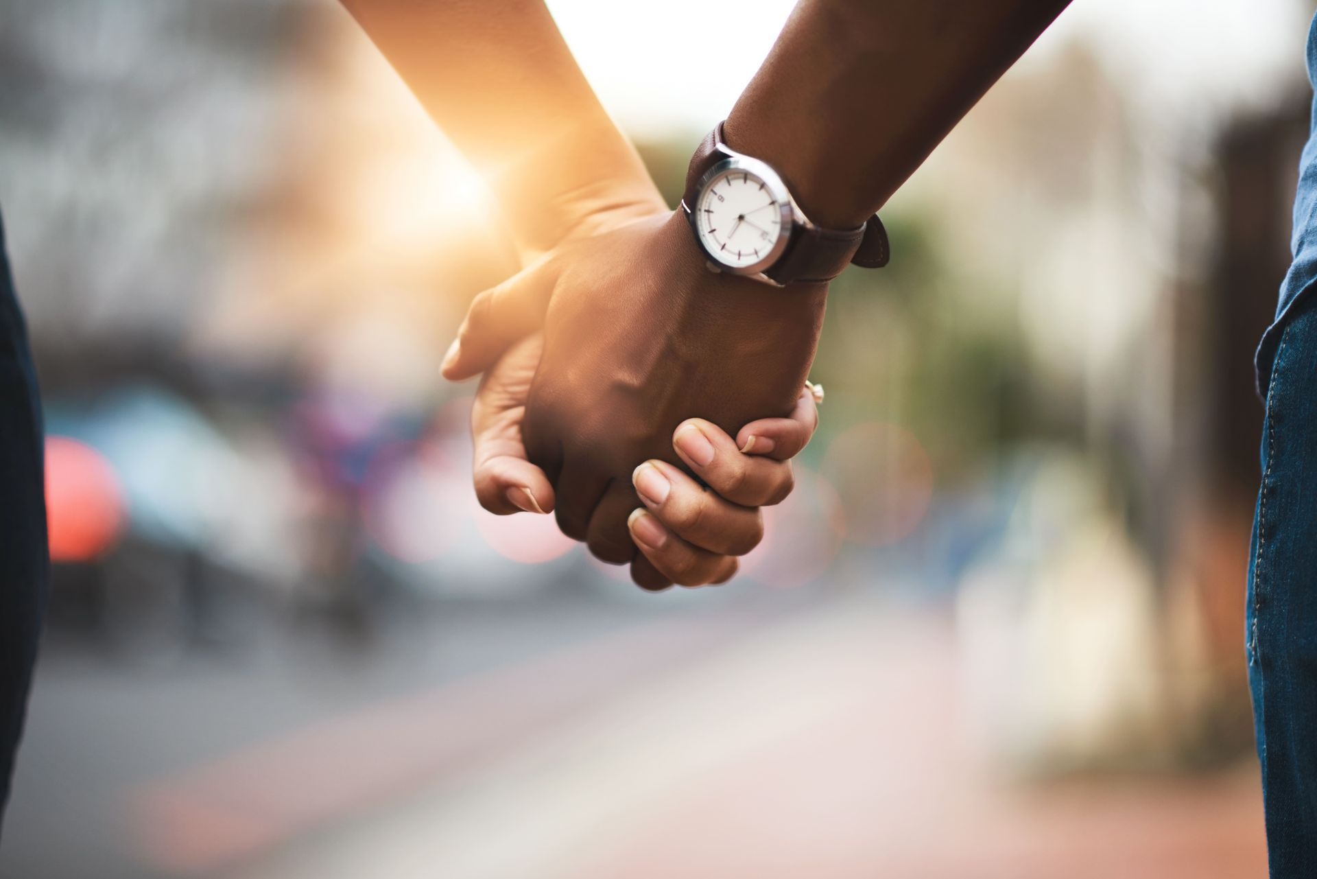 A man and a woman are holding hands on a city street.