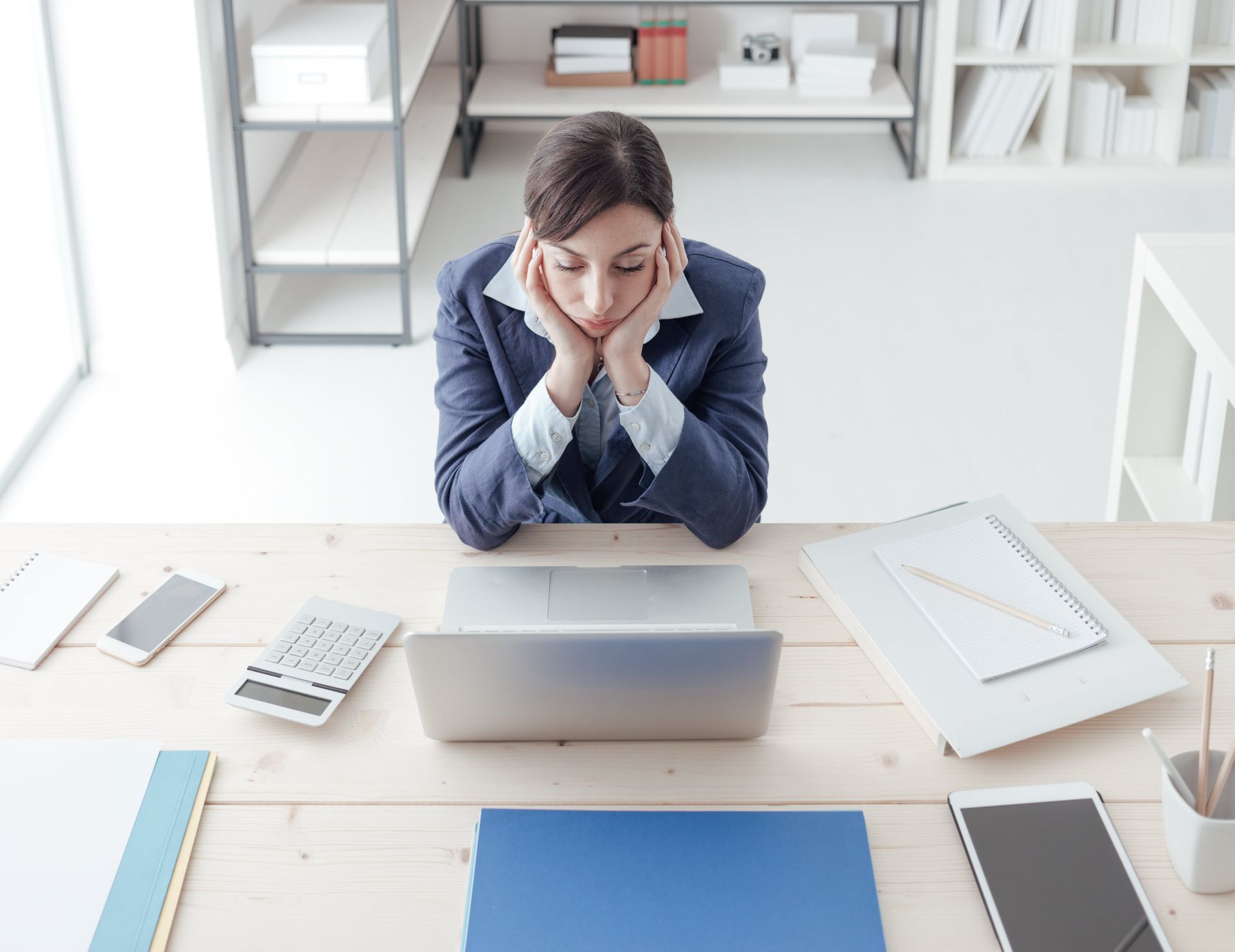 A woman is sitting at a desk in front of a laptop computer.
