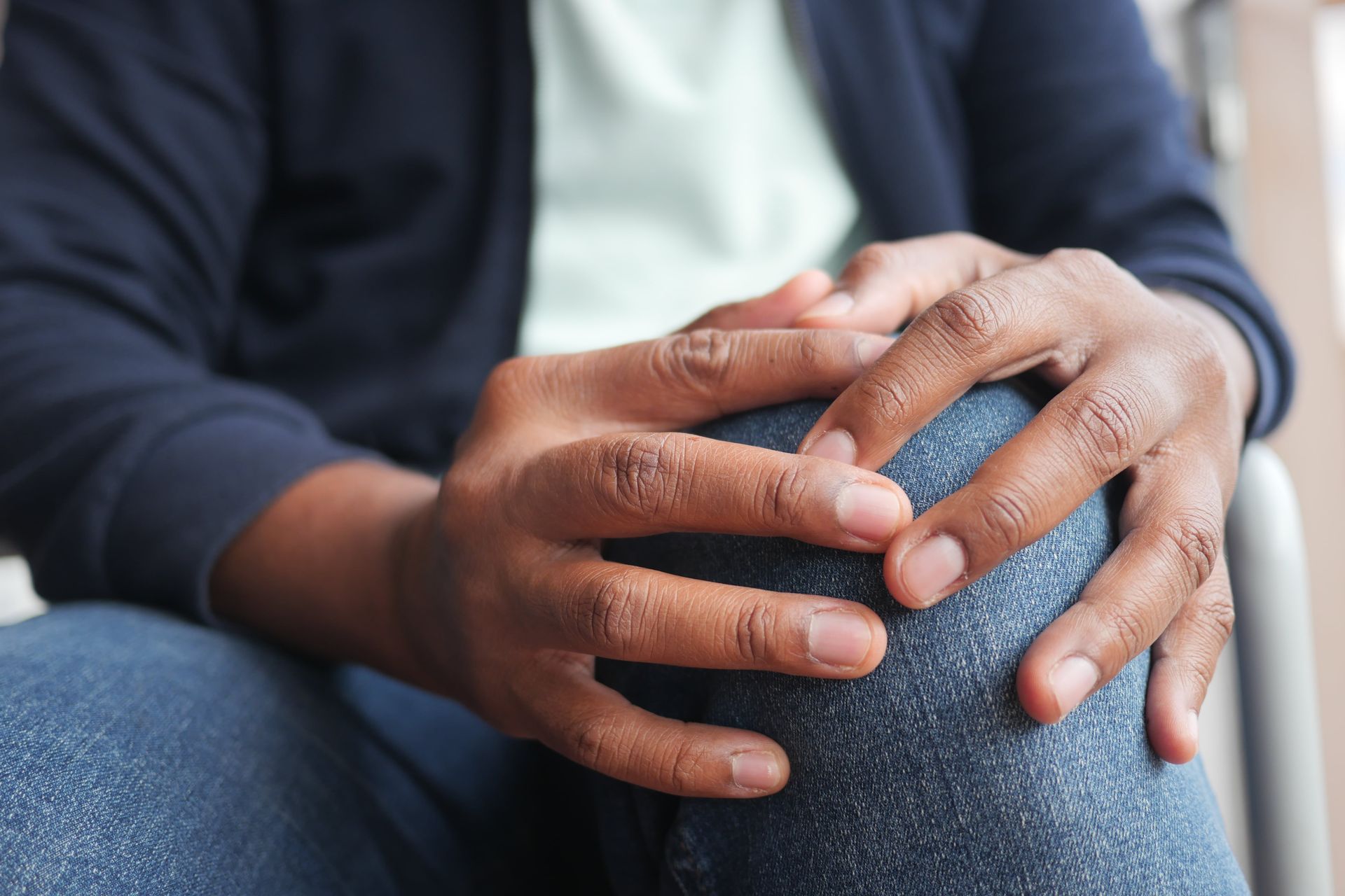 A man is sitting in a chair with his hands on his knees.