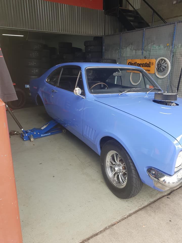 A Man Is Working on A Car on A Lift in A Garage — Budget Tyre Shed In Charmhaven, NSW