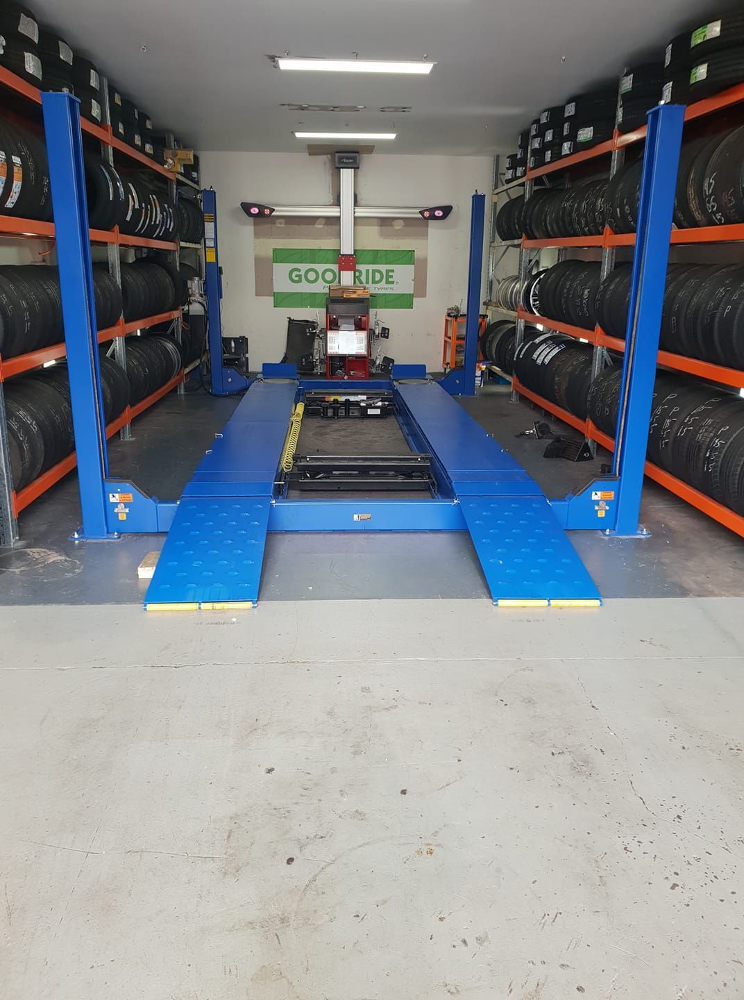 A Man Is Changing a Tire on A Car in A Garage — Budget Tyre Shed In Charmhaven, NSW
