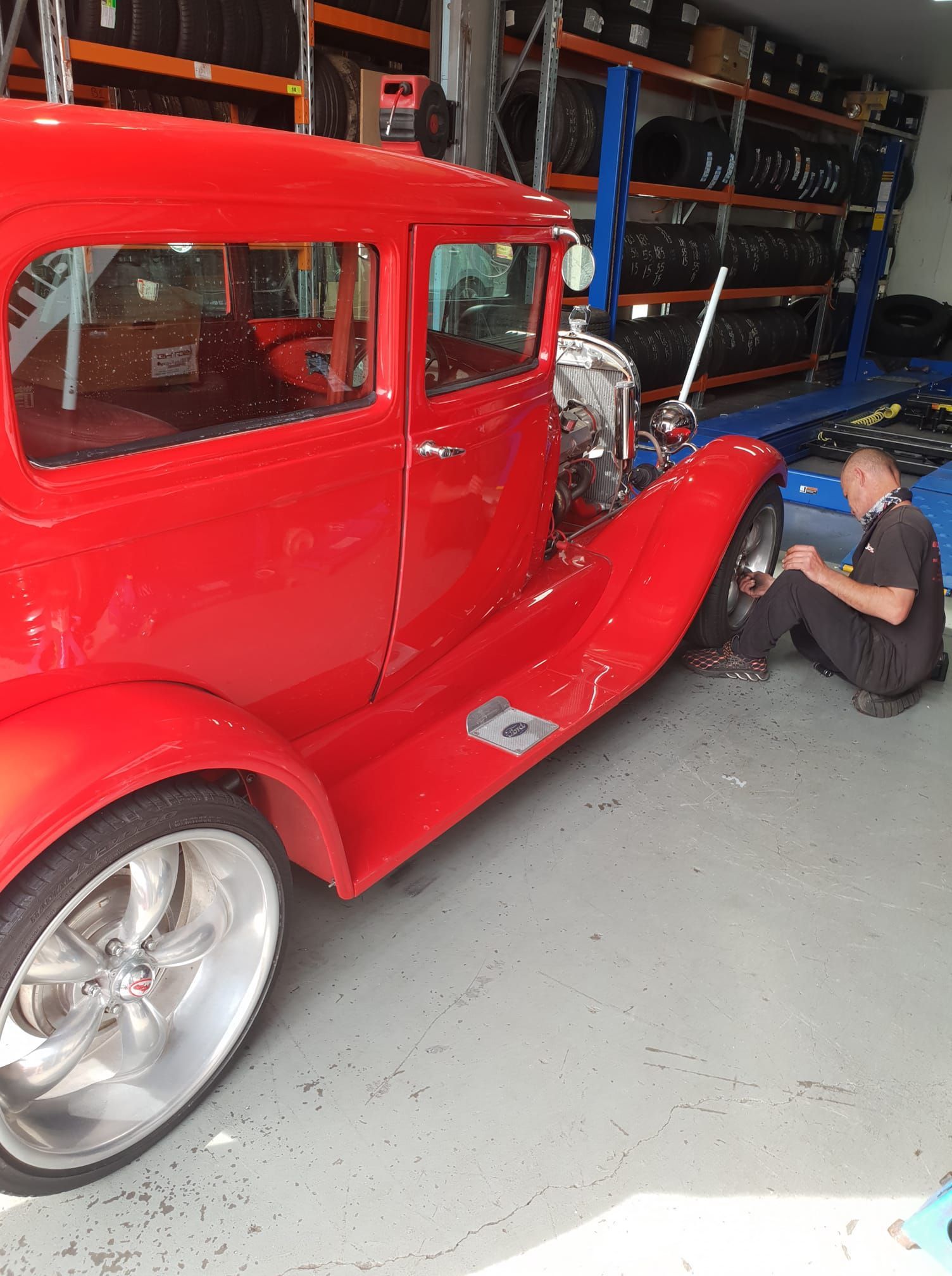 A Man Is Balancing a Tire on A Machine — Budget Tyre Shed In Charmhaven, NSW