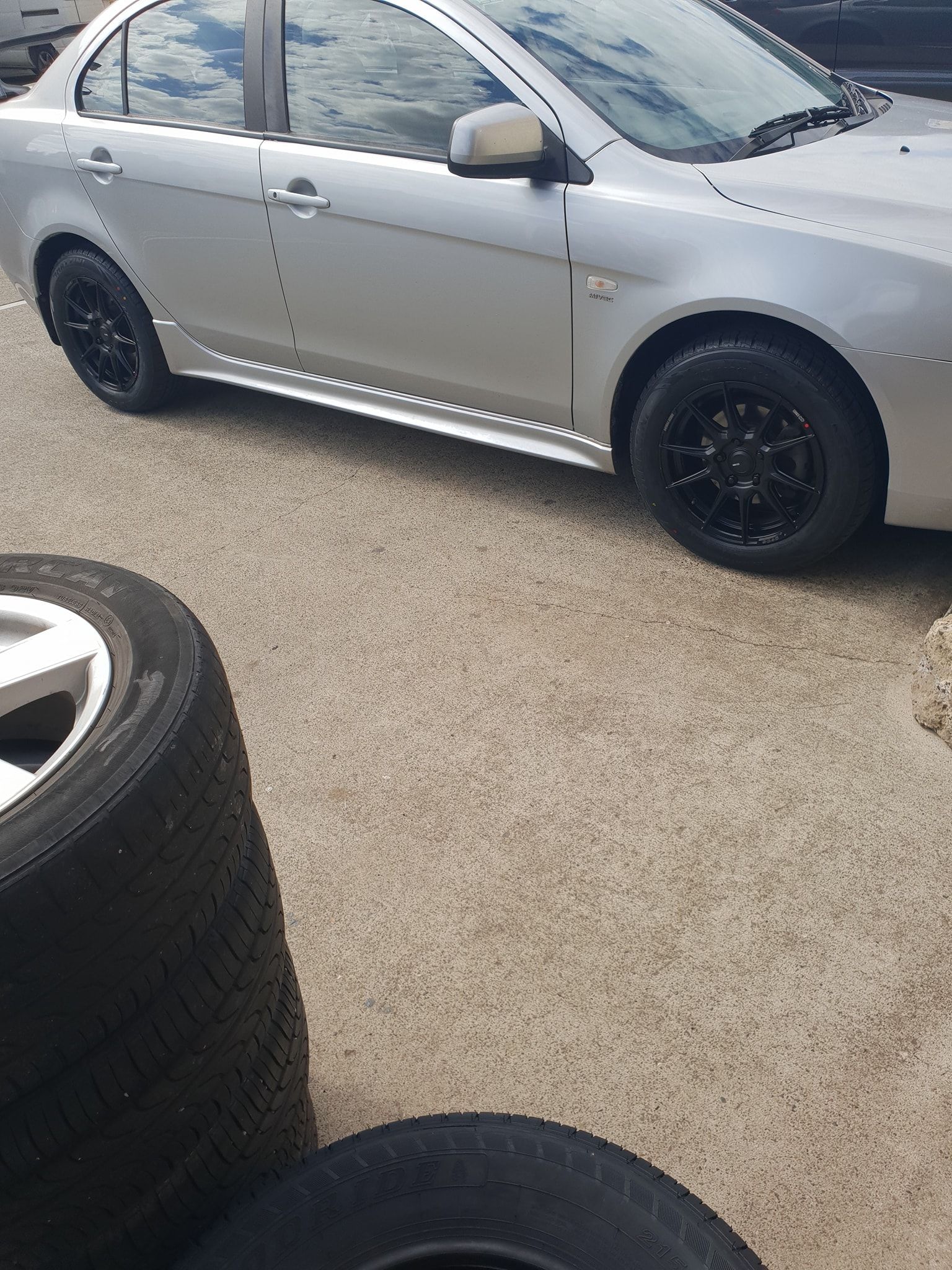A Man Is Working on A Tire with A Wrench — Budget Tyre Shed In Charmhaven, NSW