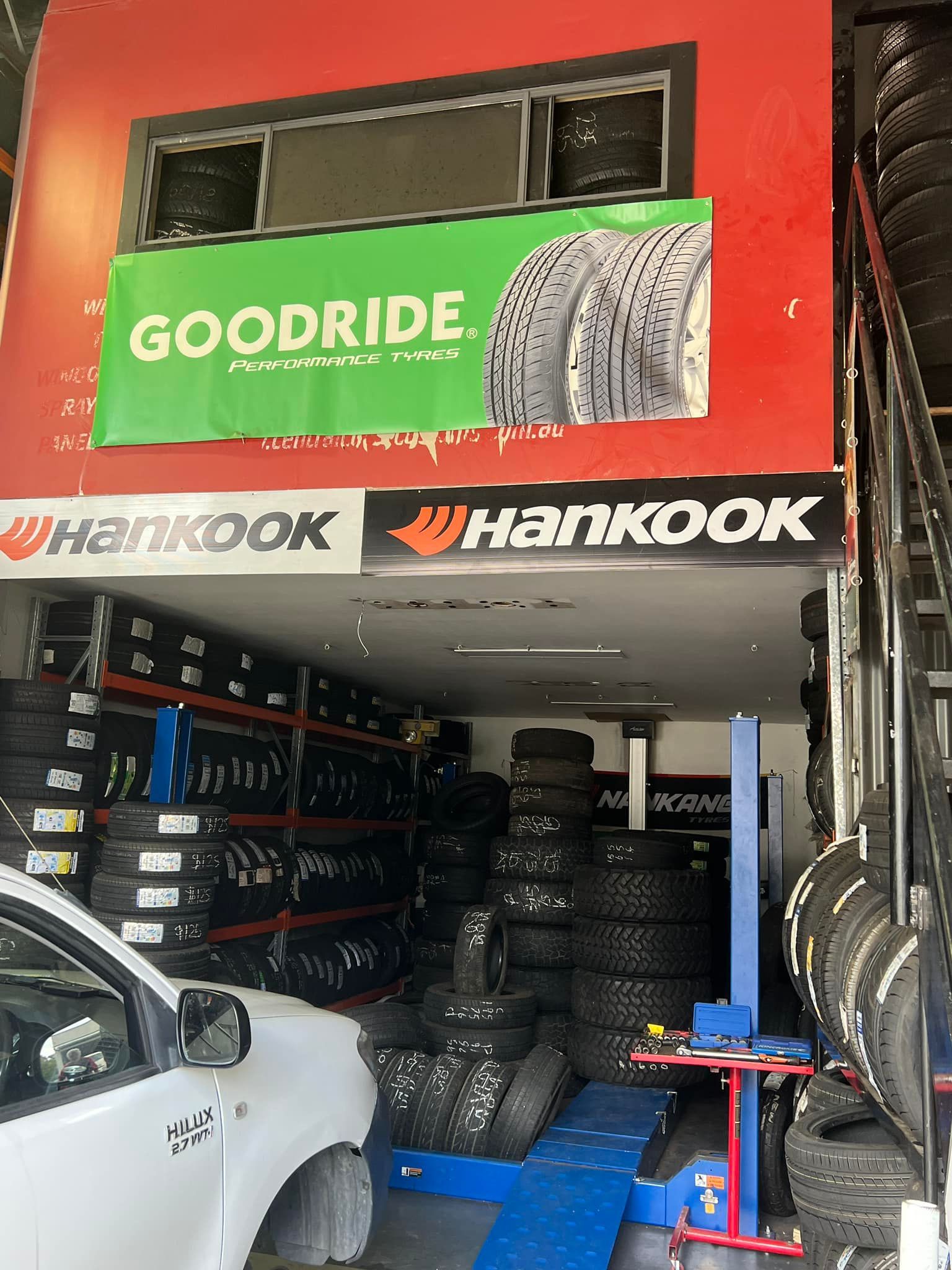 A Man Is Changing a Tire on A Car in A Garage — Budget Tyre Shed In Charmhaven, NSW