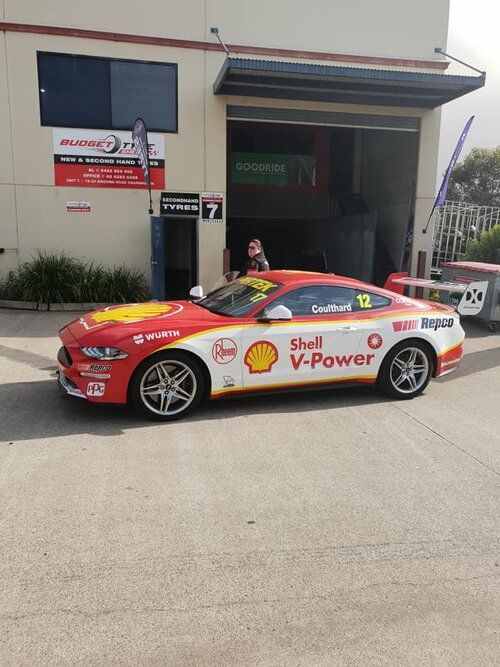 A Red and White Race Car Is Parked in Front of A Building — Budget Tyre Shed In Charmhaven, NSW
