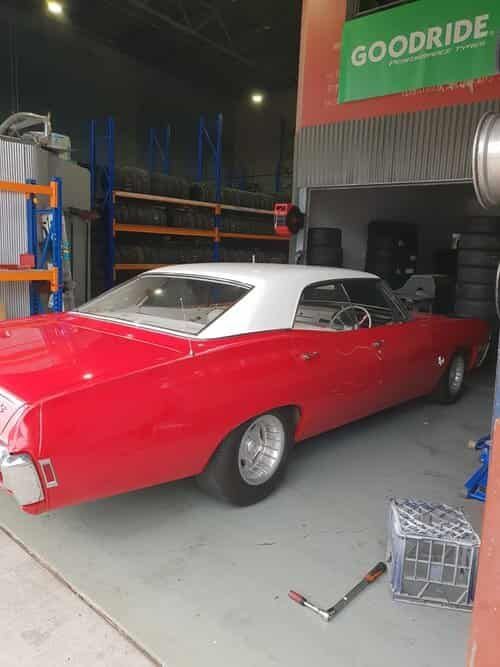 A Red Car Is Parked in A Garage in Front of A Goodride Sign — Budget Tyre Shed In Charmhaven, NSW