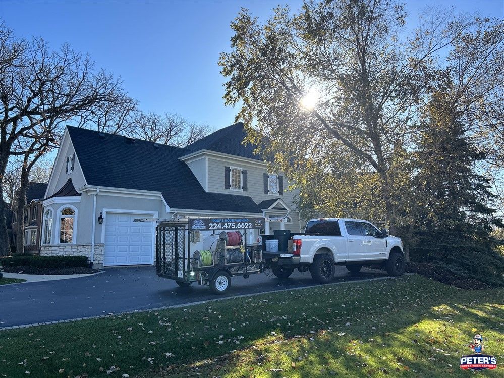 Image of a house in Hoffman Estates getting a power wash. You can see a two story home with a long driveway and a power washing truck in the driveway