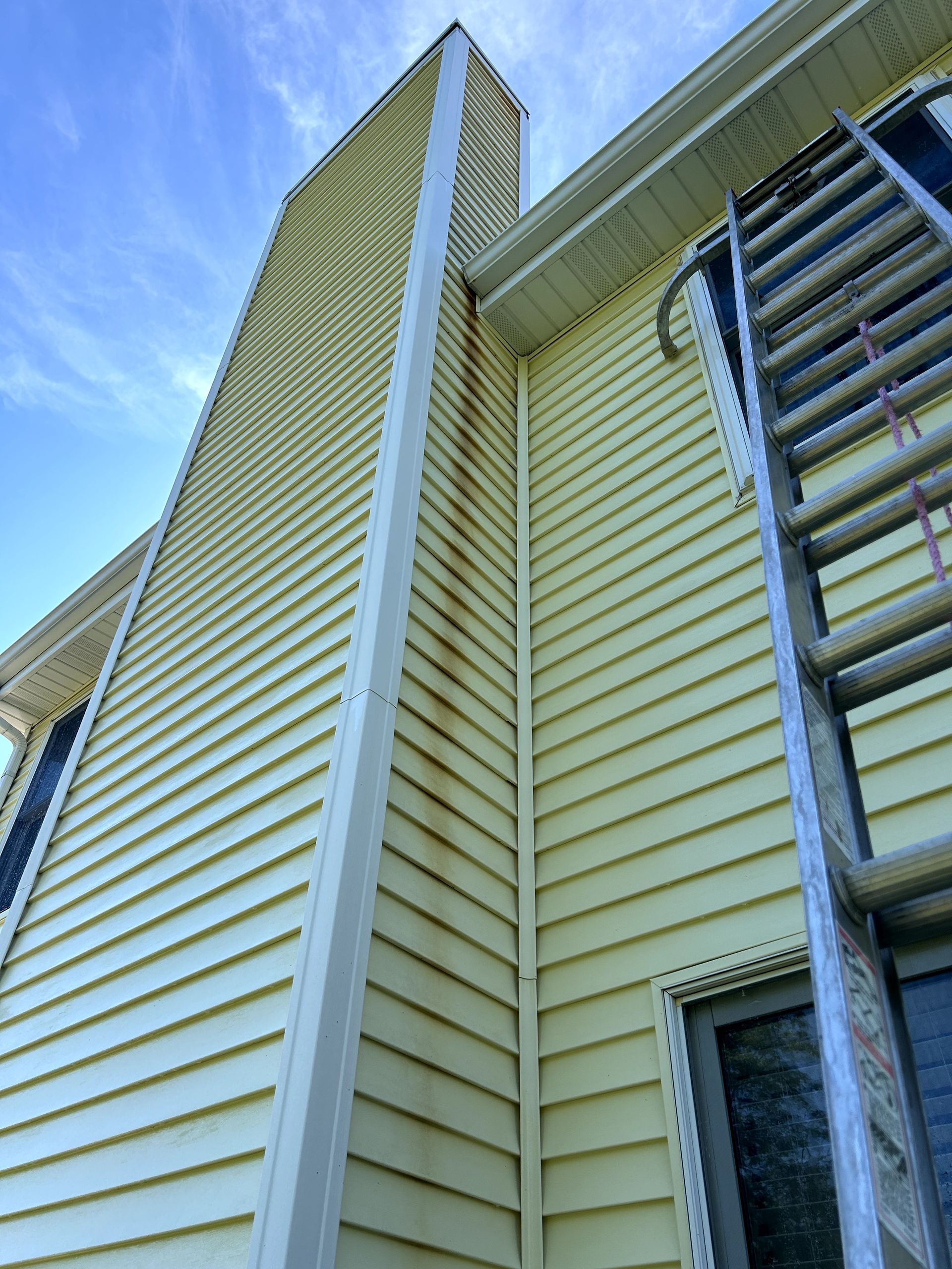 Image of Peter's Power Washing cleaning windows on a two story house. 