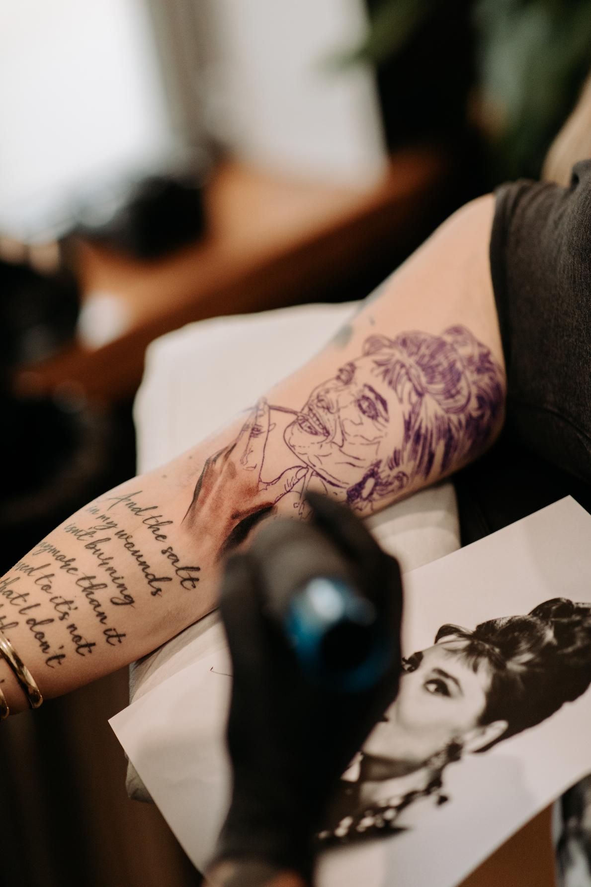 A Person is Getting a Tattoo of Audrey Hepburn on Their Arm — Gallery Tattoo in Medowie, NSW