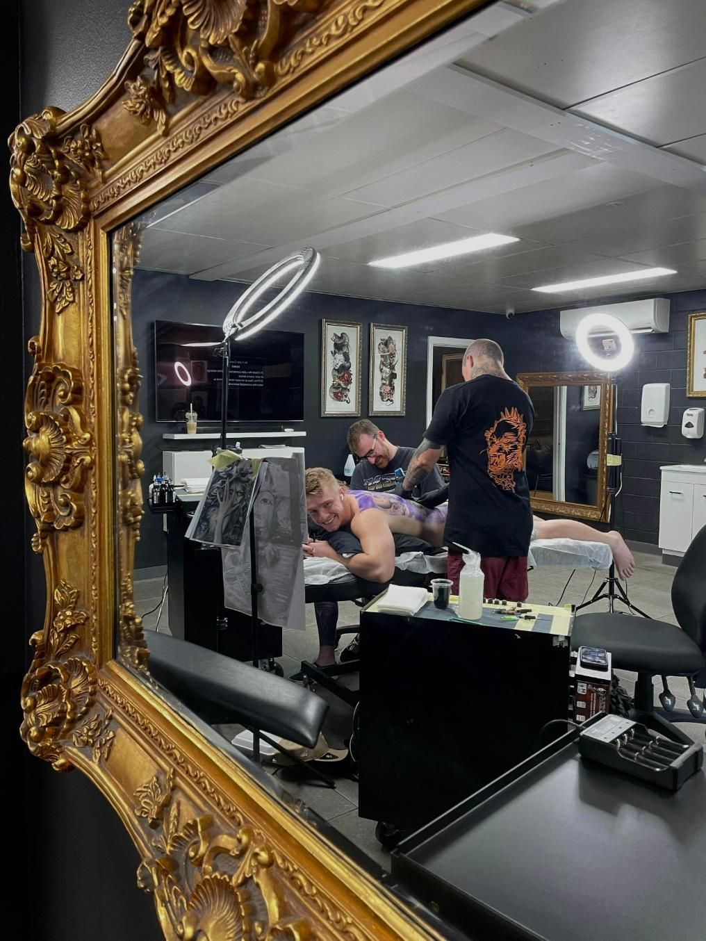 A Man is Getting a Tattoo in a Tattoo Studio in Front of a Mirror — Gallery Tattoo in Medowie, NSW