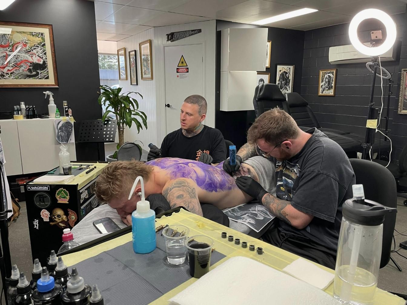 A Man is Getting a Tattoo on His Back in a Tattoo Shop — Gallery Tattoo in Medowie, NSW