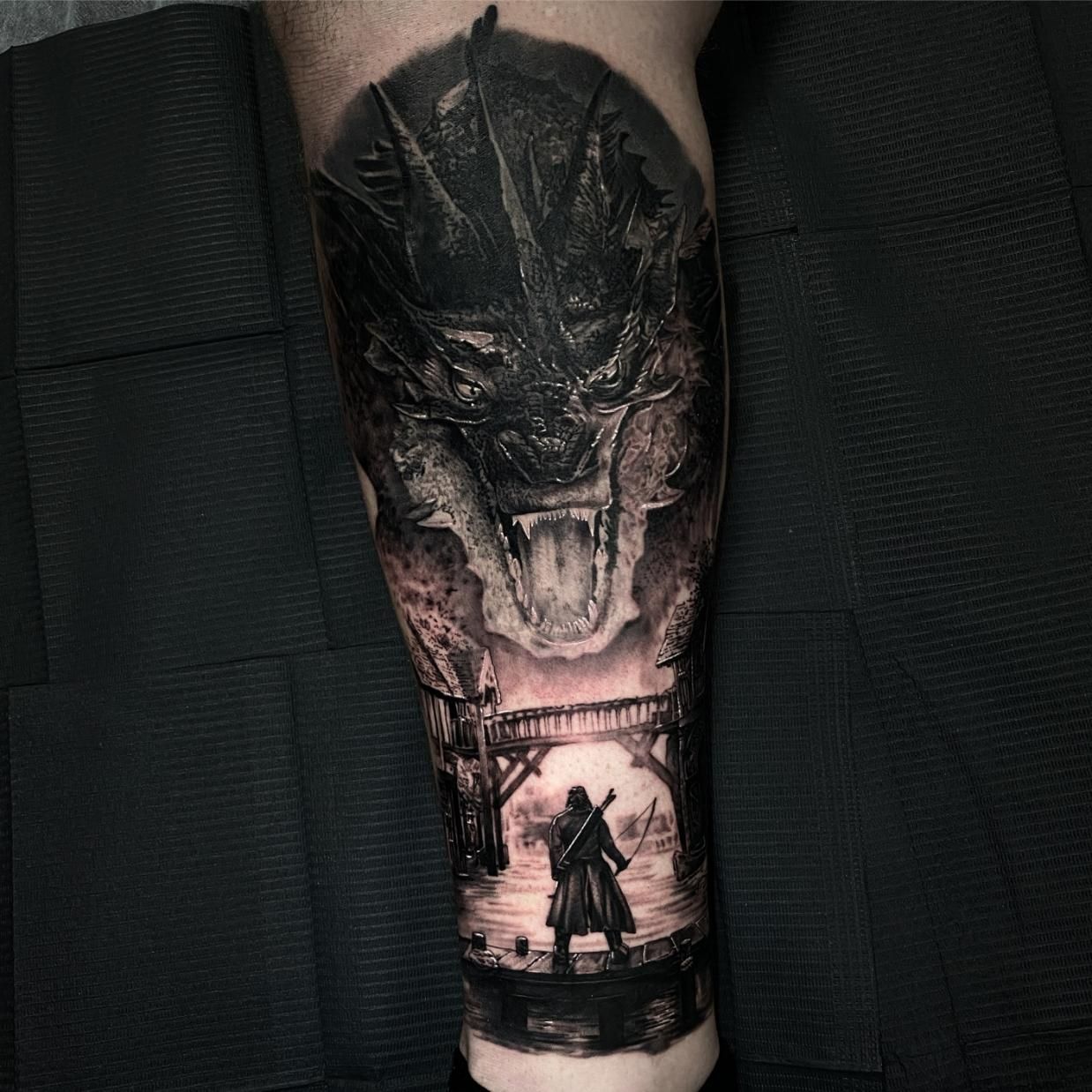 A Black and White Tattoo of a Man and a Dragon on a Leg — Gallery Tattoo in Medowie, NSW