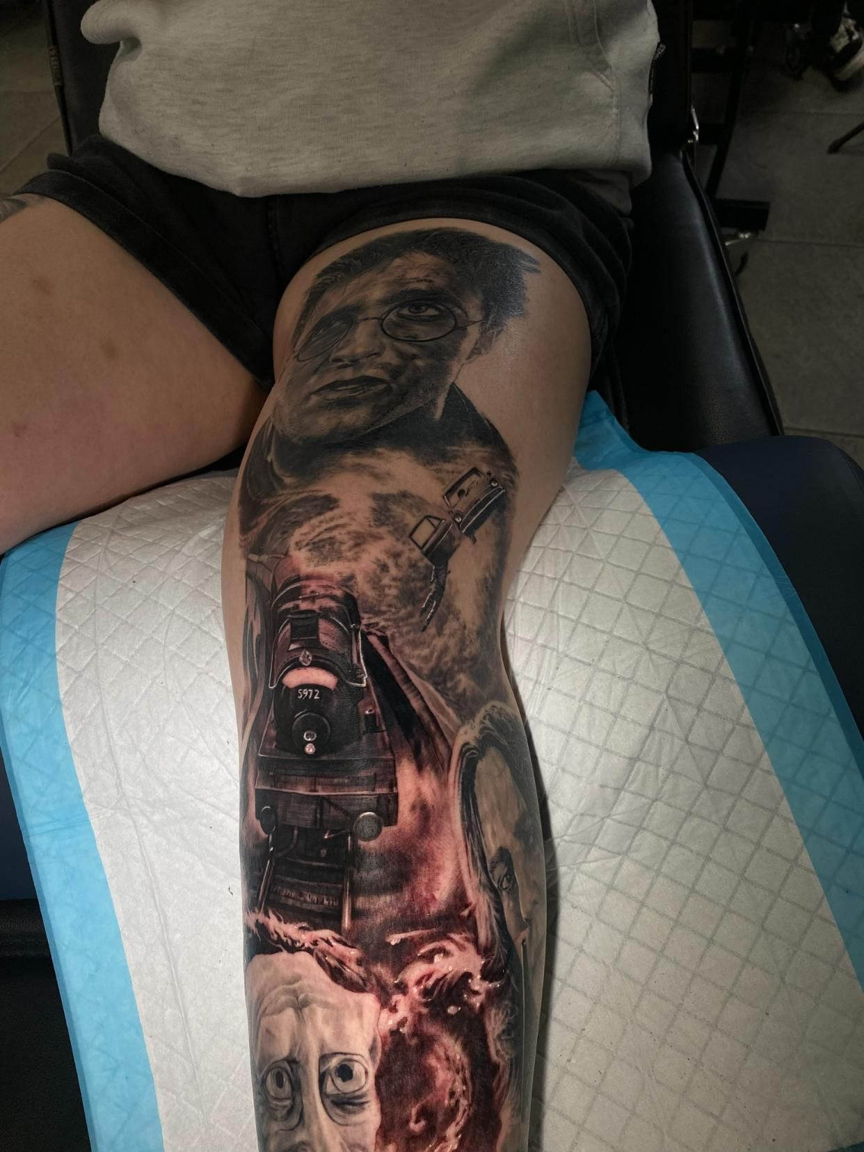 A Person Has a Tattoo on Their Leg of a Man and a Train — Gallery Tattoo in Medowie, NSW