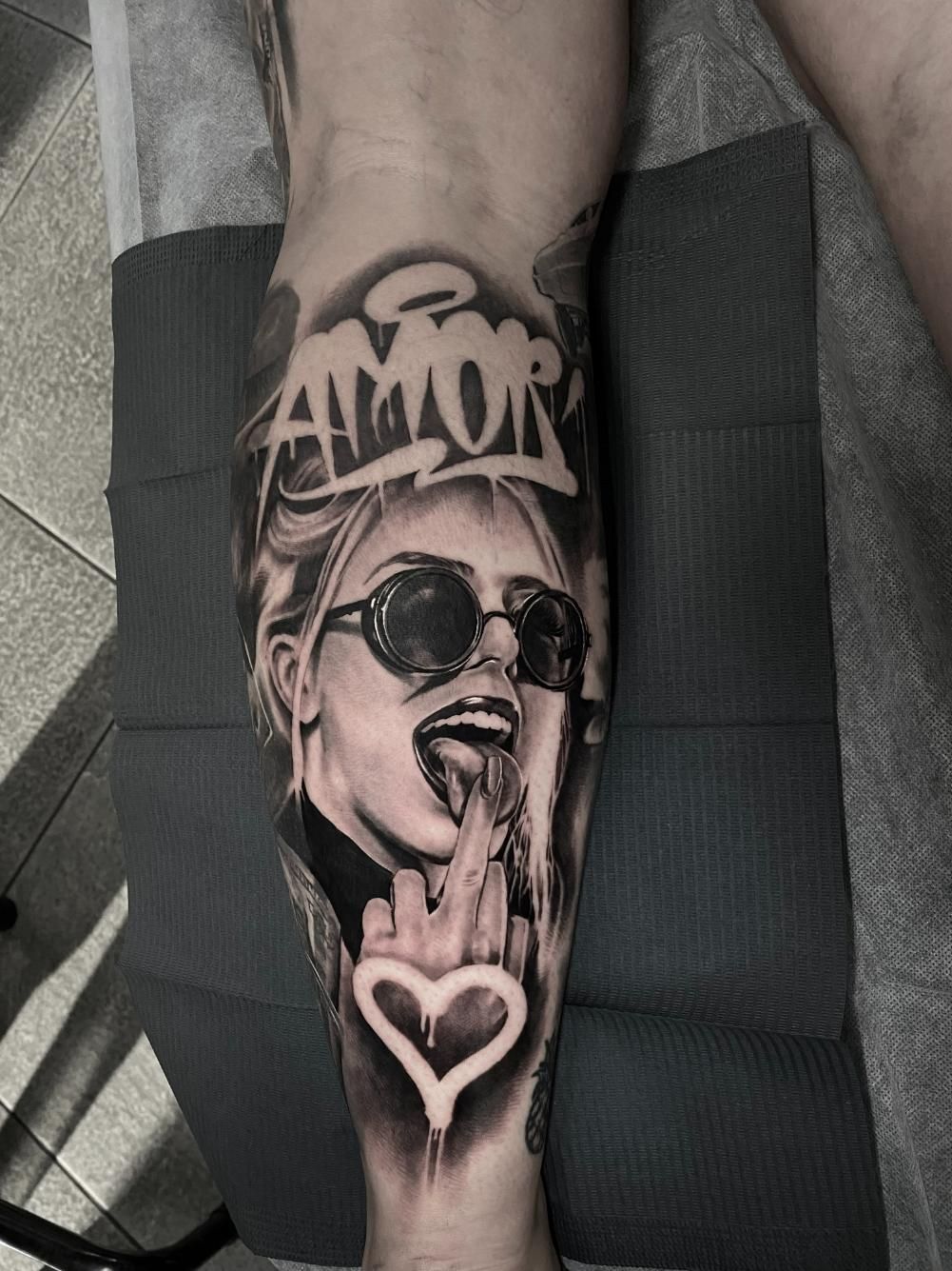 A Black and White Tattoo of a Woman With Sunglasses on Her Leg — Gallery Tattoo in Medowie, NSW
