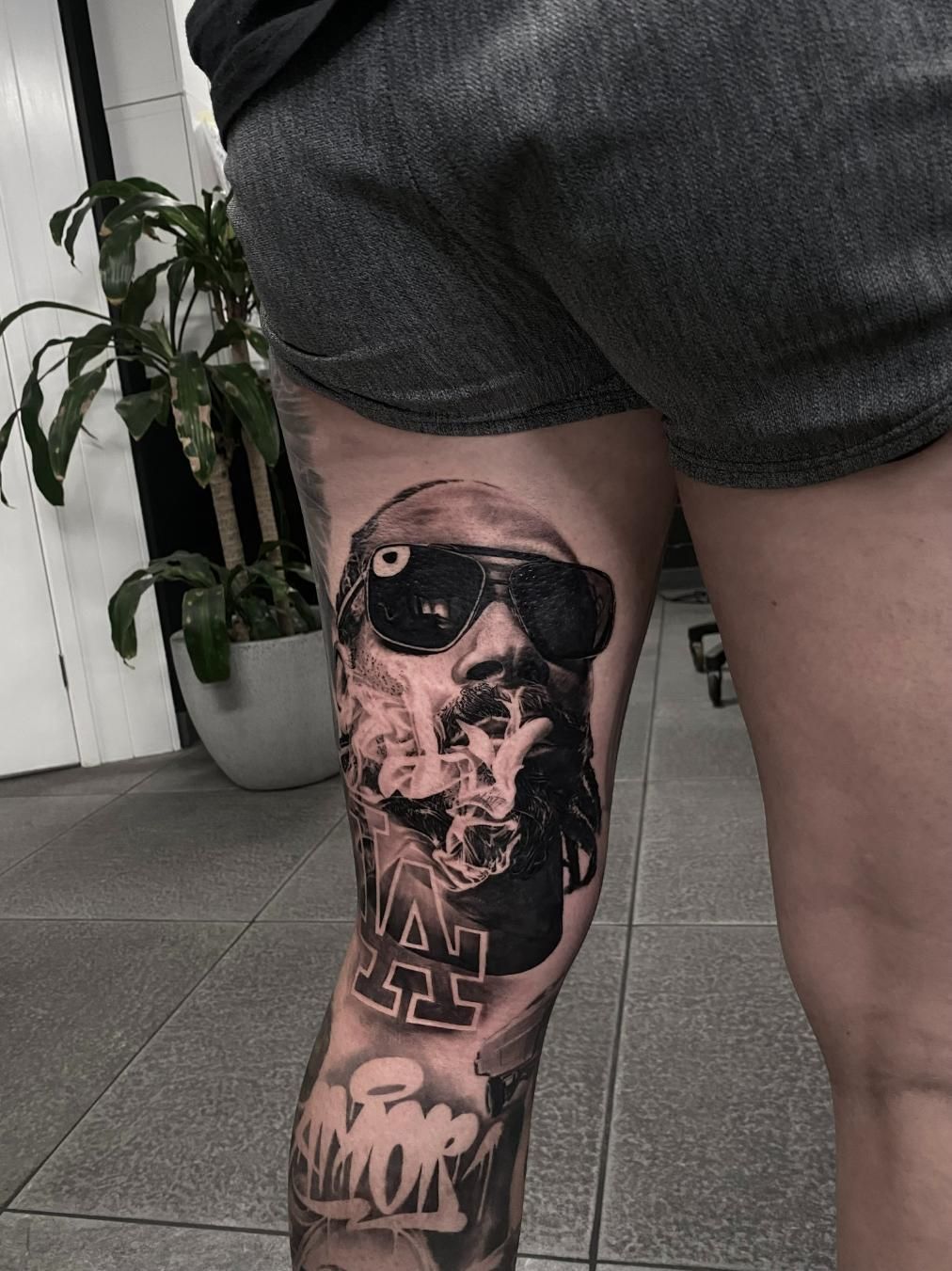 A Woman Has a Tattoo of a Man Wearing Sunglasses on Her Leg — Gallery Tattoo in Medowie, NSW
