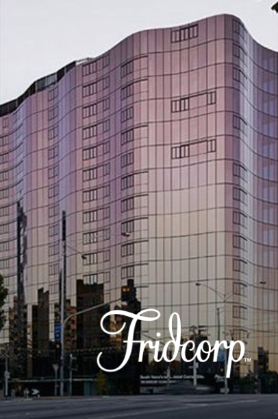 Pink glass Fridcarporp building, street level view, cloudy sky.