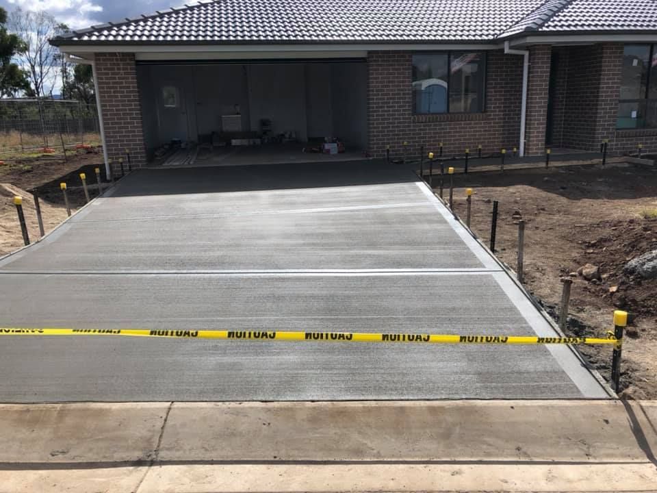 Newly Poured Concrete Driveway in Front of a Brick House — Heritage Concrete In Uralla, NSW
