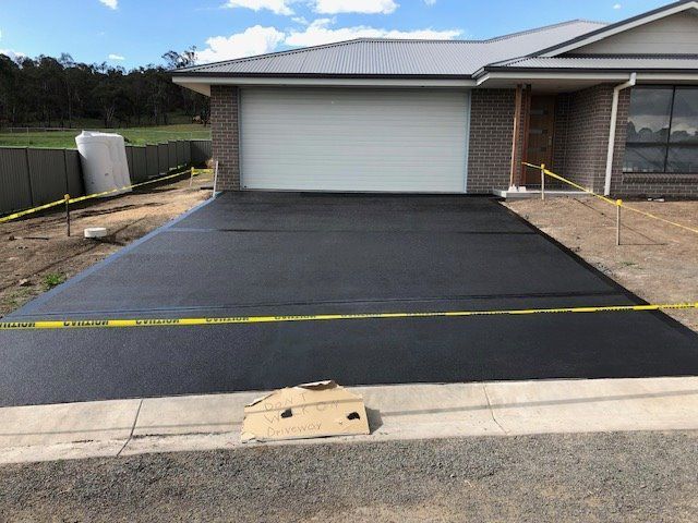 Freshly Paved Black Driveway in Front of a Modern House — Heritage Concrete In Uralla, NSW