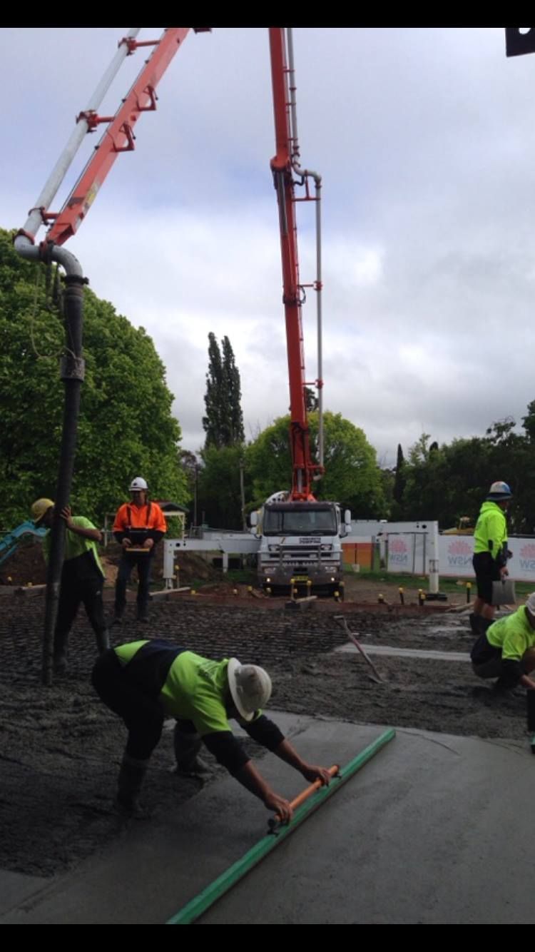 Construction Workers Leveling Wet Concrete With a Screed — Heritage Concrete In Uralla, NSW
