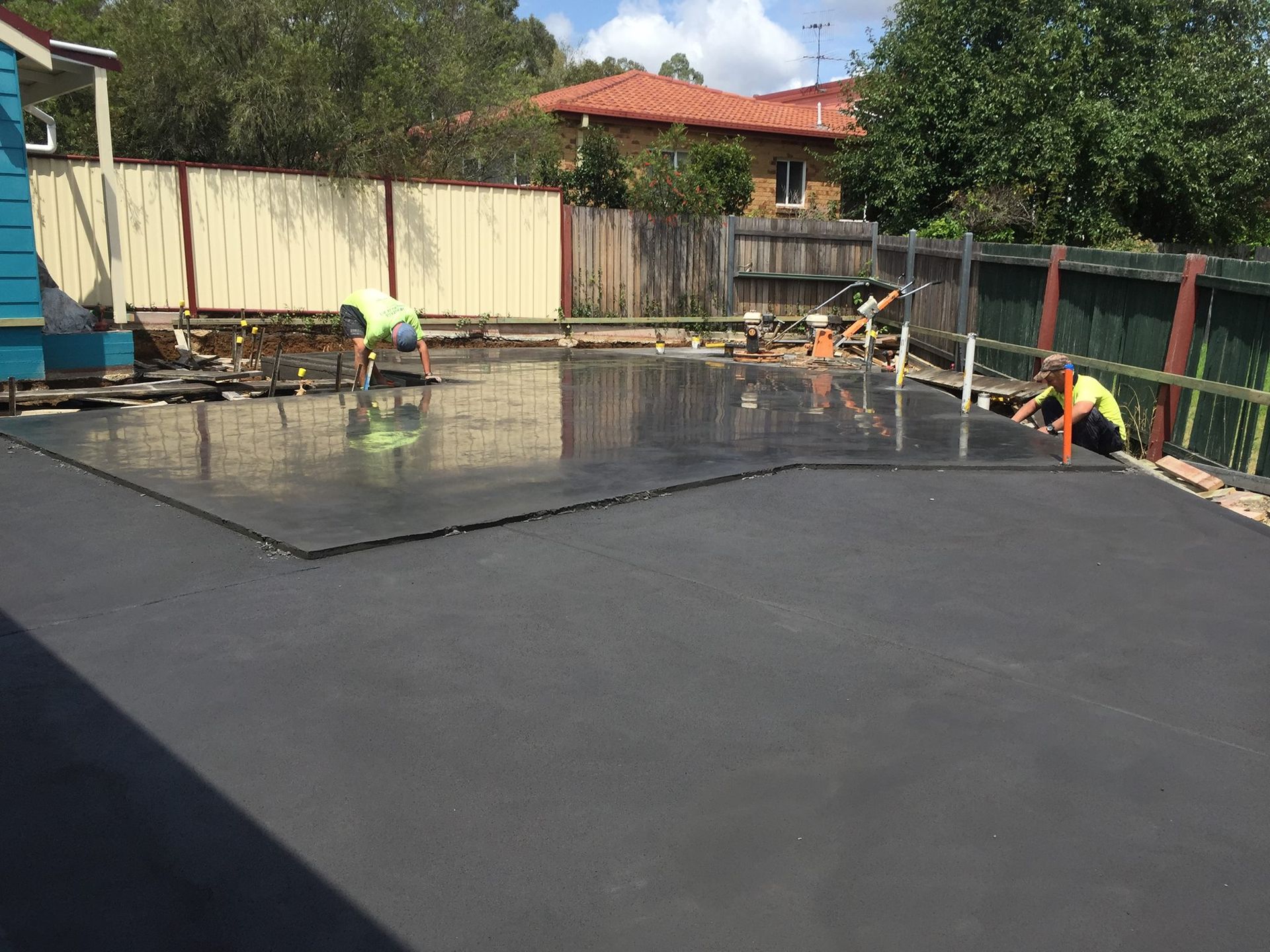 Workers Smoothing Fresh Concrete on a Backyard Patio — Heritage Concrete In Uralla, NSW