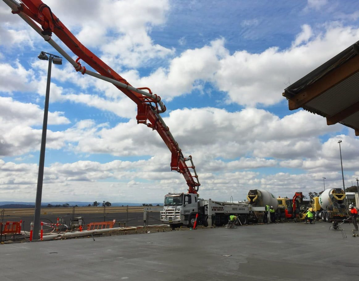 A Concrete Pump Is Being Used To Pour Concrete Into A Parking Lot — Heritage Concrete In Guyra, NSW