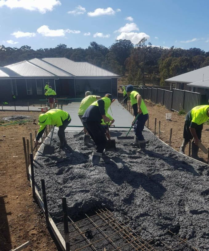 A Group Of Construction Workers Are Working On A Concrete Slab — Heritage Concrete In Uralla, NSW