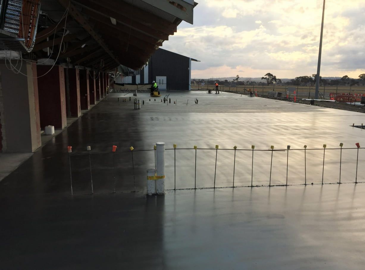 A Man Is Standing On A Concrete Floor In Front Of A Building — Heritage Concrete In Uralla, NSW