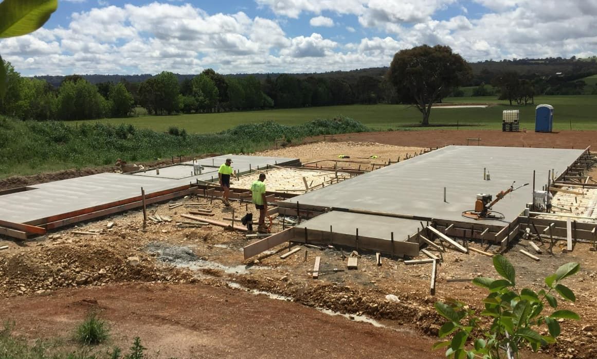 A Group Of Construction Workers Are Working On A Concrete Base For A House — Heritage Concrete In Uralla, NSW