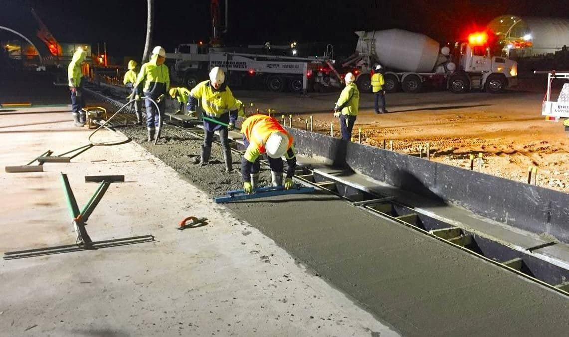 A Group Of Construction Workers Are Working On A Road At Night — Heritage Concrete In Uralla, NSW