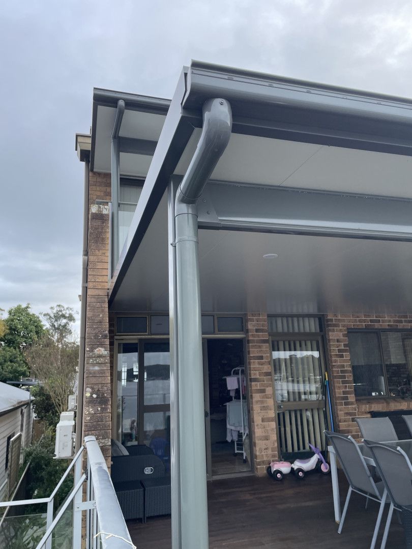 Corner of A House with Tan Siding, White Trim, and A Downspout — Hi Tech Roofing in Kilaben Bay, NSW