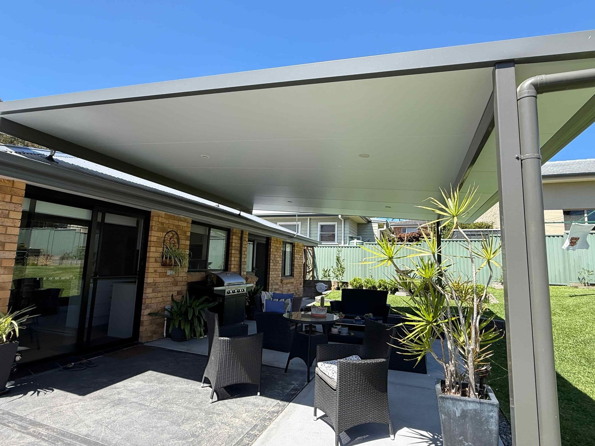 Person Using a Drill to Fasten a Red Metal Roof Panel — Hi Tech Roofing in Maitland, NSW