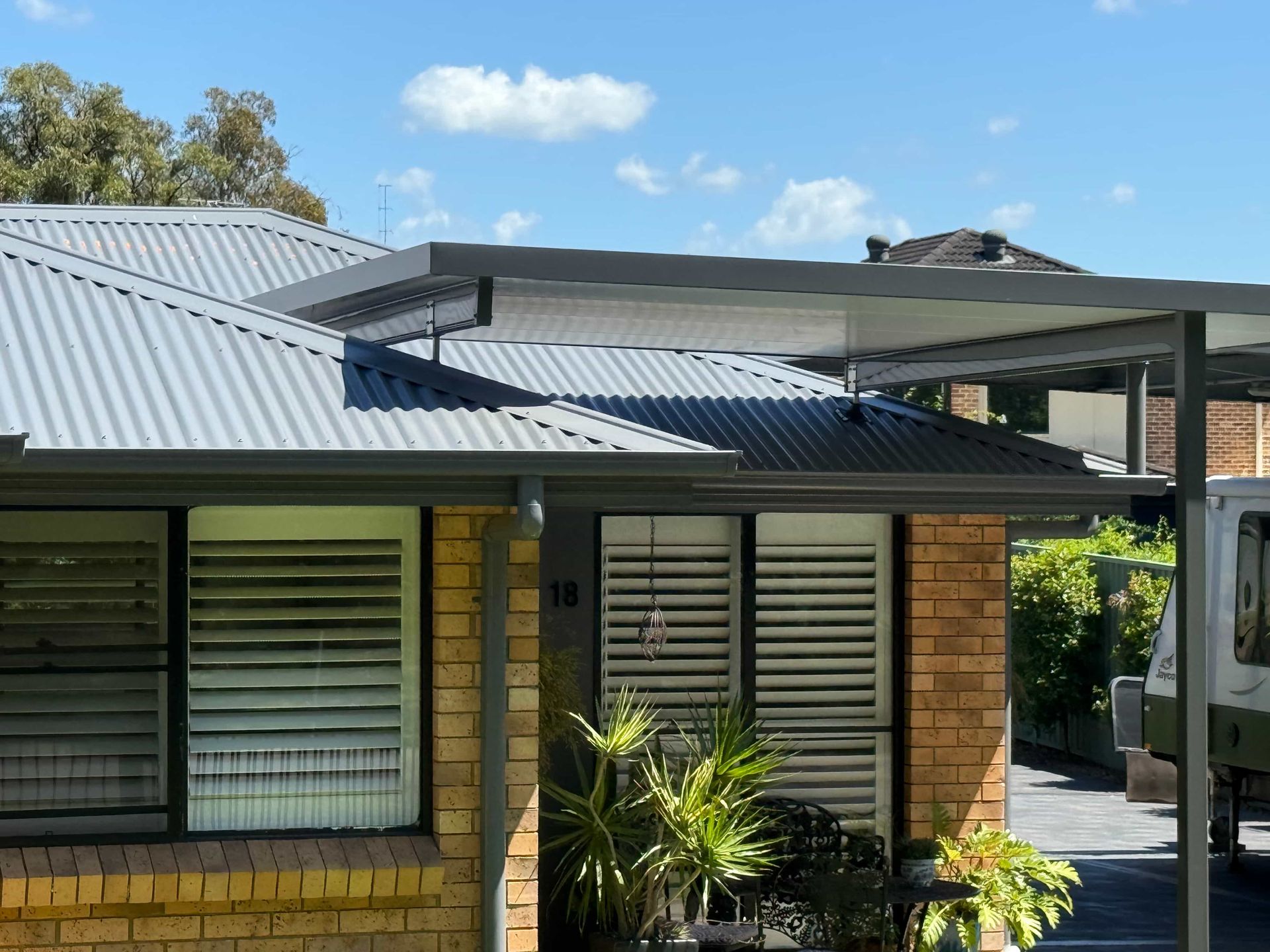 Brown Tile Roof with A Metal Chimney Against a Blue Sky — Hi Tech Roofing in Maitland, NSW
