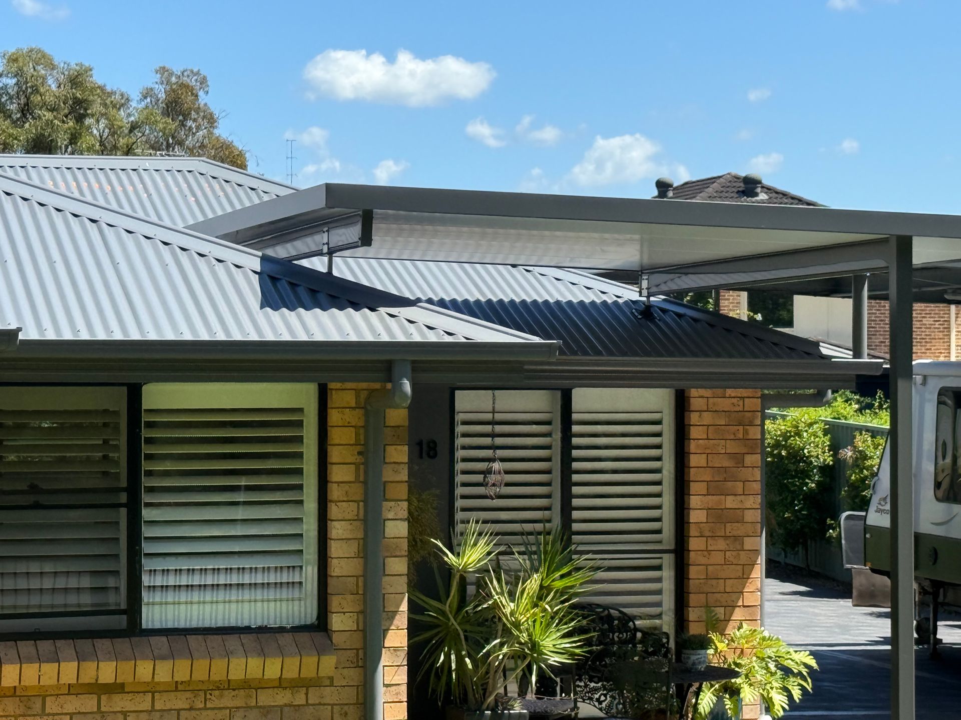 Gray Metal Roof with Ridge, Gutters, and Building in The Background — Hi Tech Roofing in Kilaben Bay, NSW