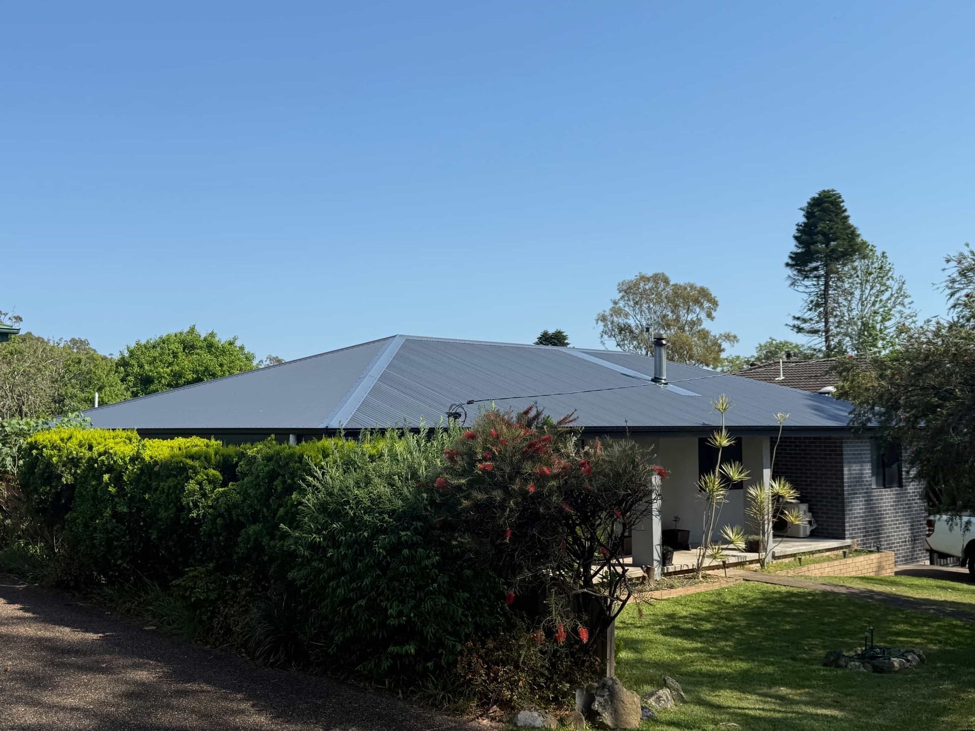 Blue-roofed house with green foliage and grass on a sunny day.