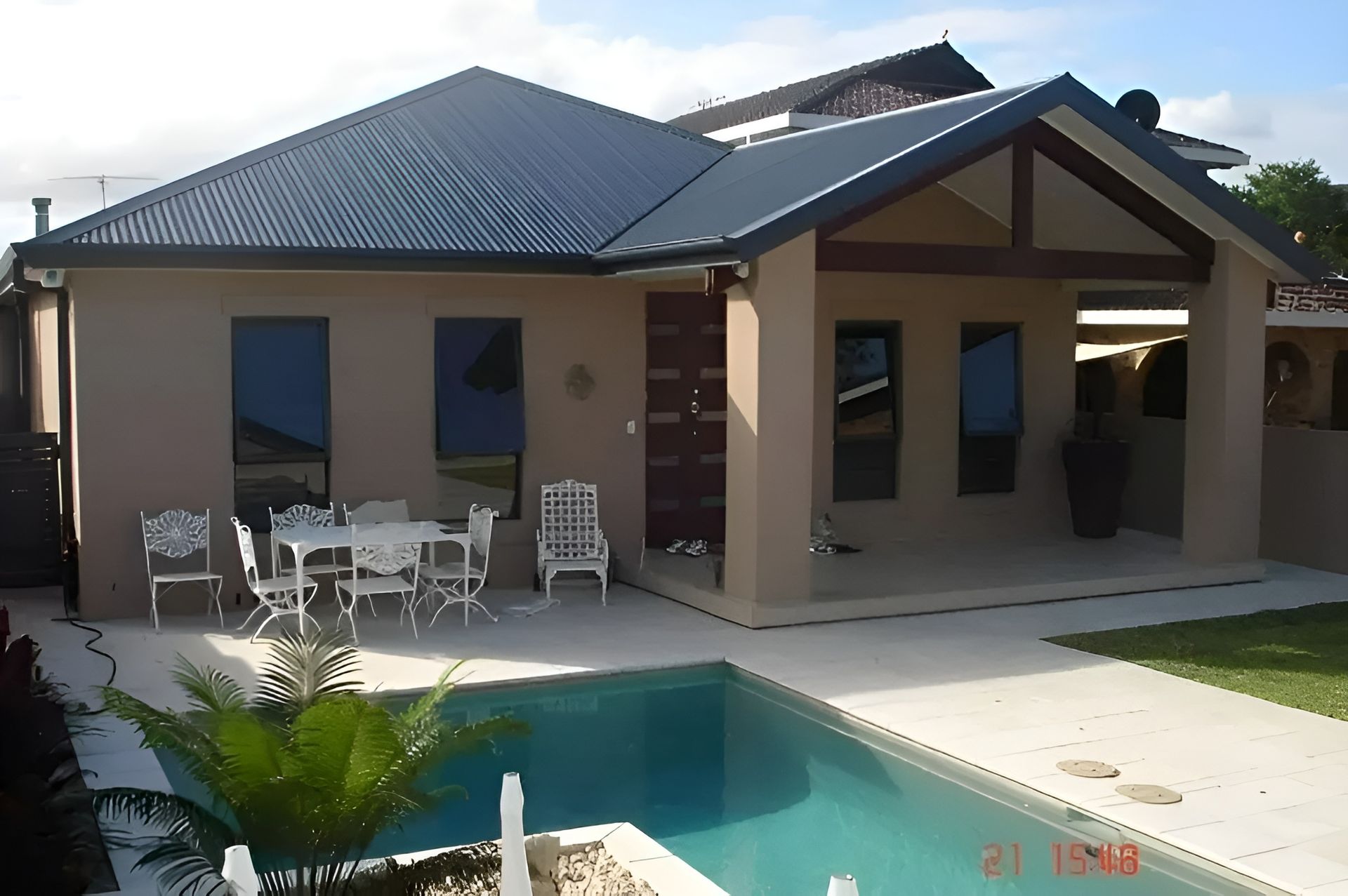 House with Pool; Beige Exterior, Dark Roof, Outdoor Dining, Blue Pool, Clear Sky — Hi Tech Roofing in Kilaben Bay, NSW