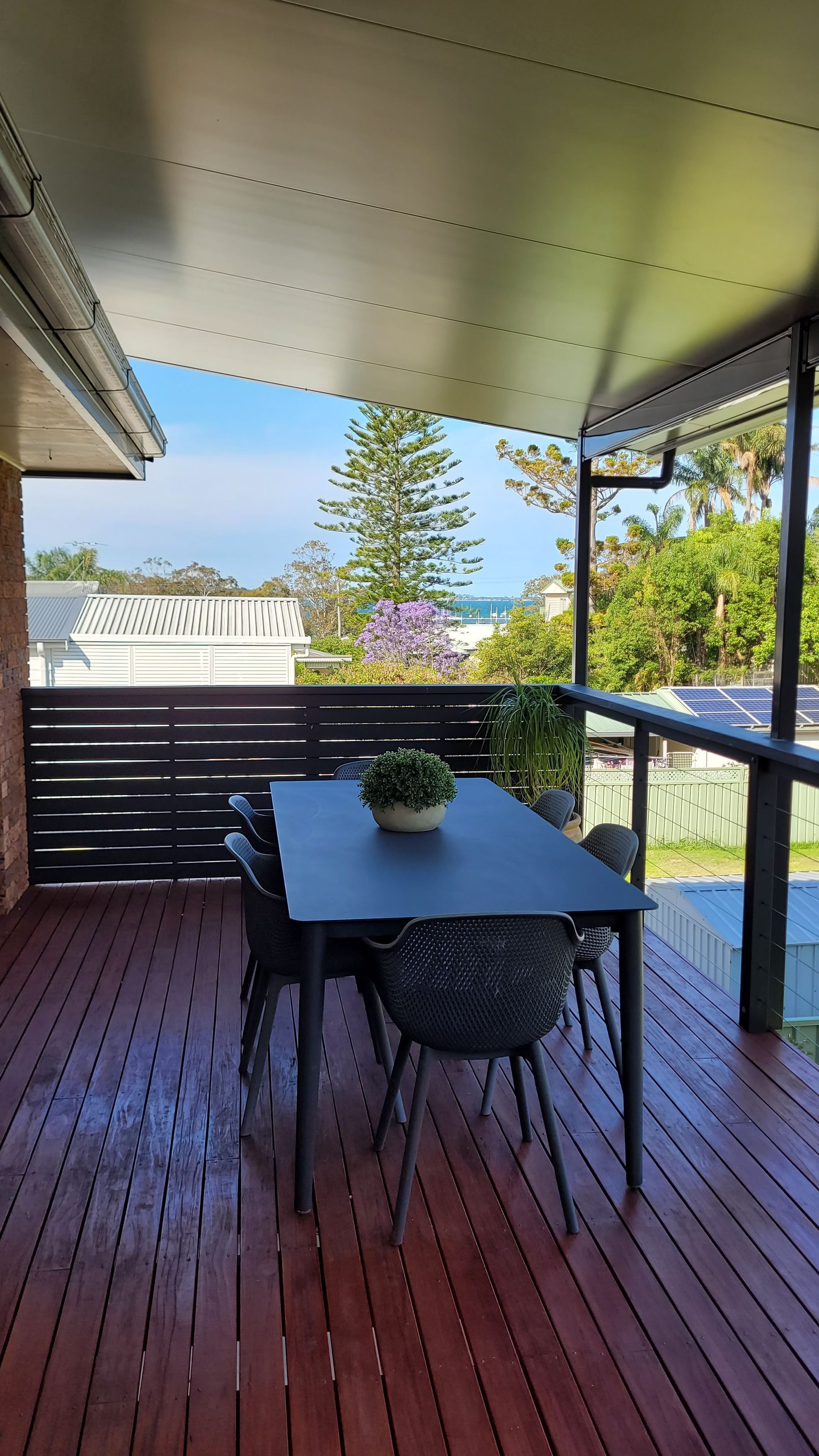 Outdoor Deck with Table and Chairs, Overlooking Ocean and Trees — Hi Tech Roofing in Kilaben Bay, NSW