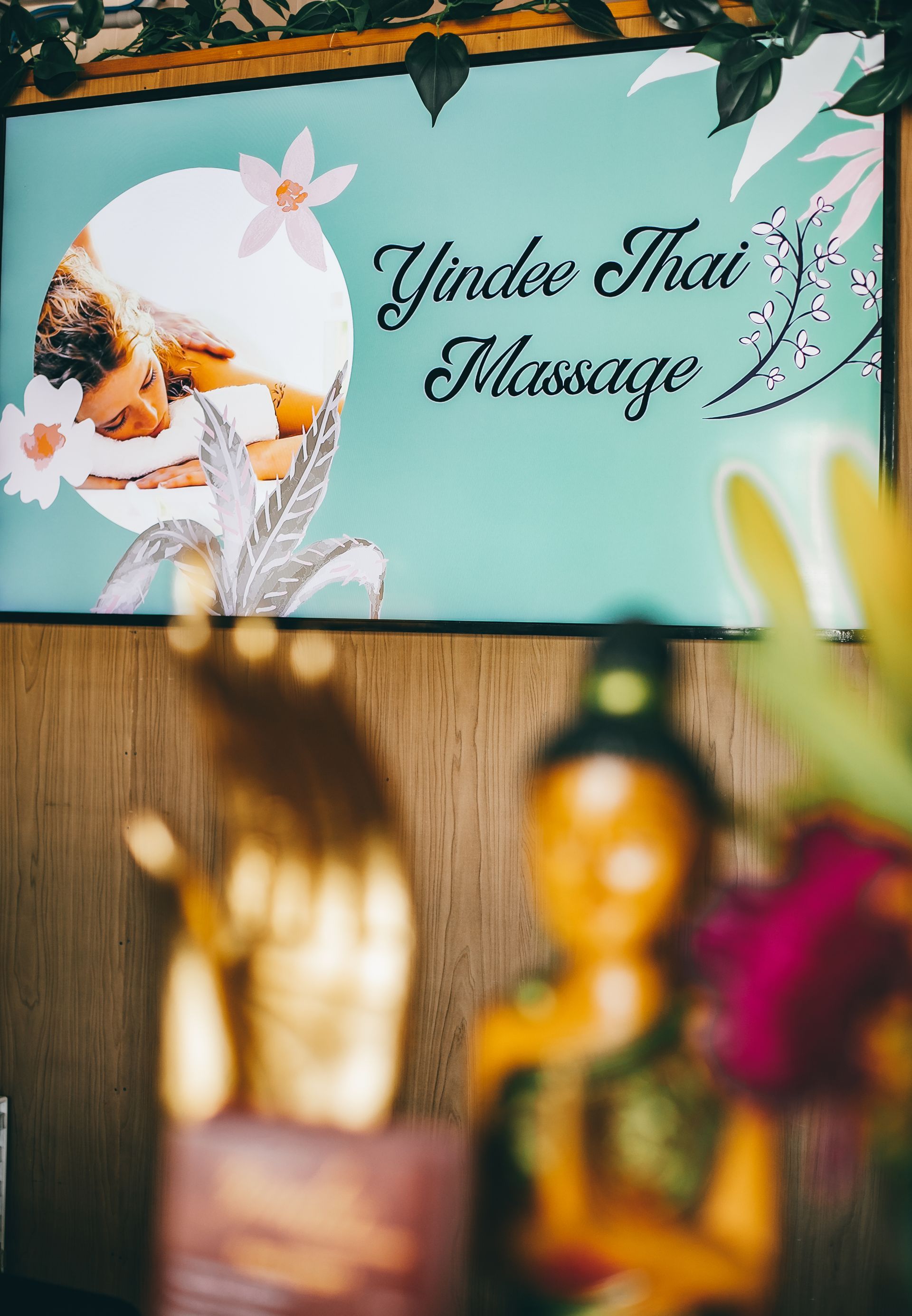 Sign for Yindee Thai Massage with woman receiving massage.