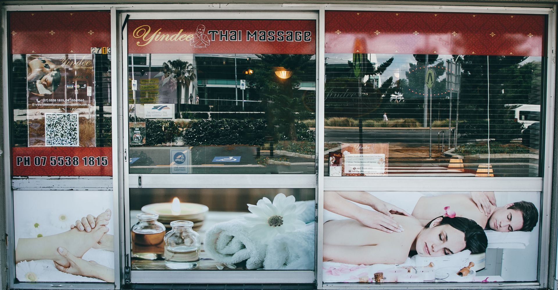 Massage parlor storefront with window displays featuring massage, candles, and flowers.