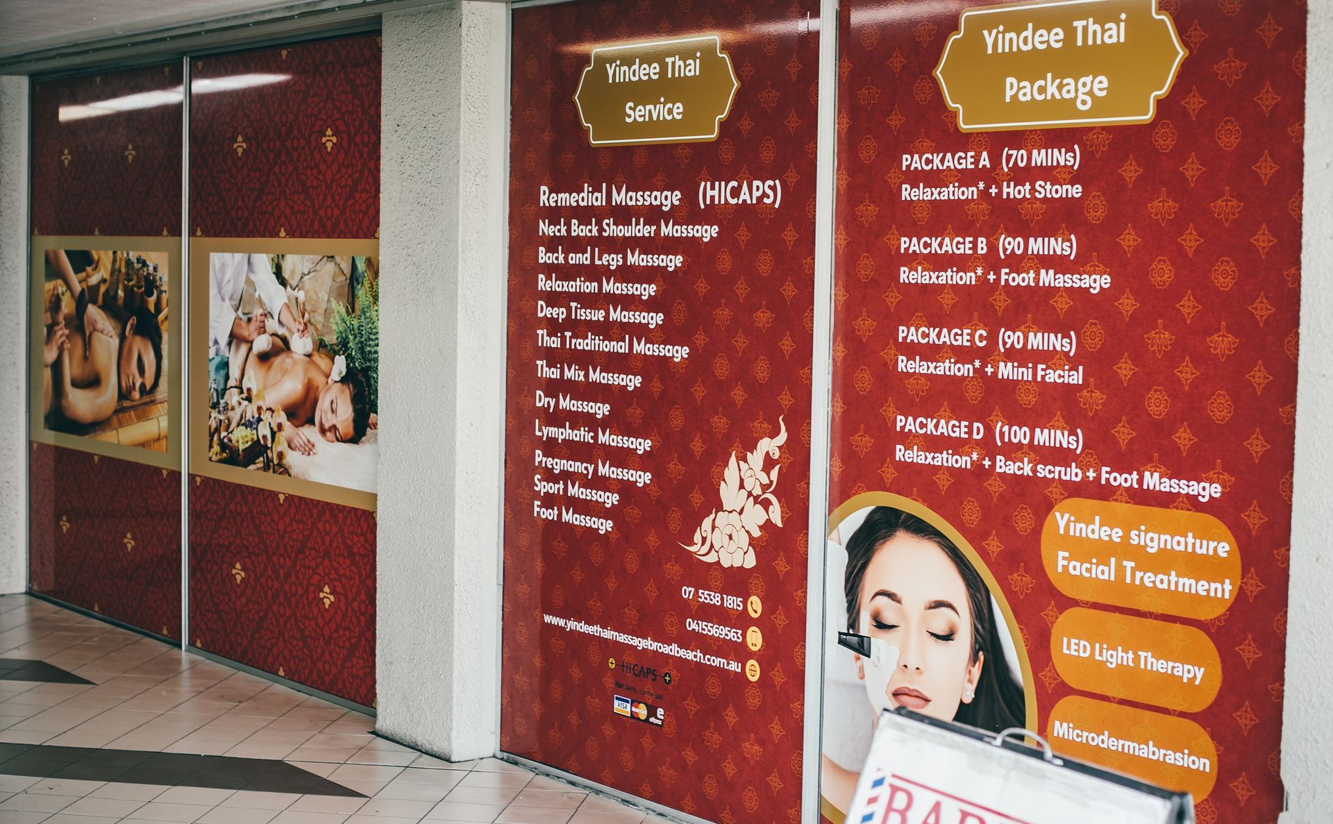 Storefront with signs advertising Thai massage services. Red and gold decor.