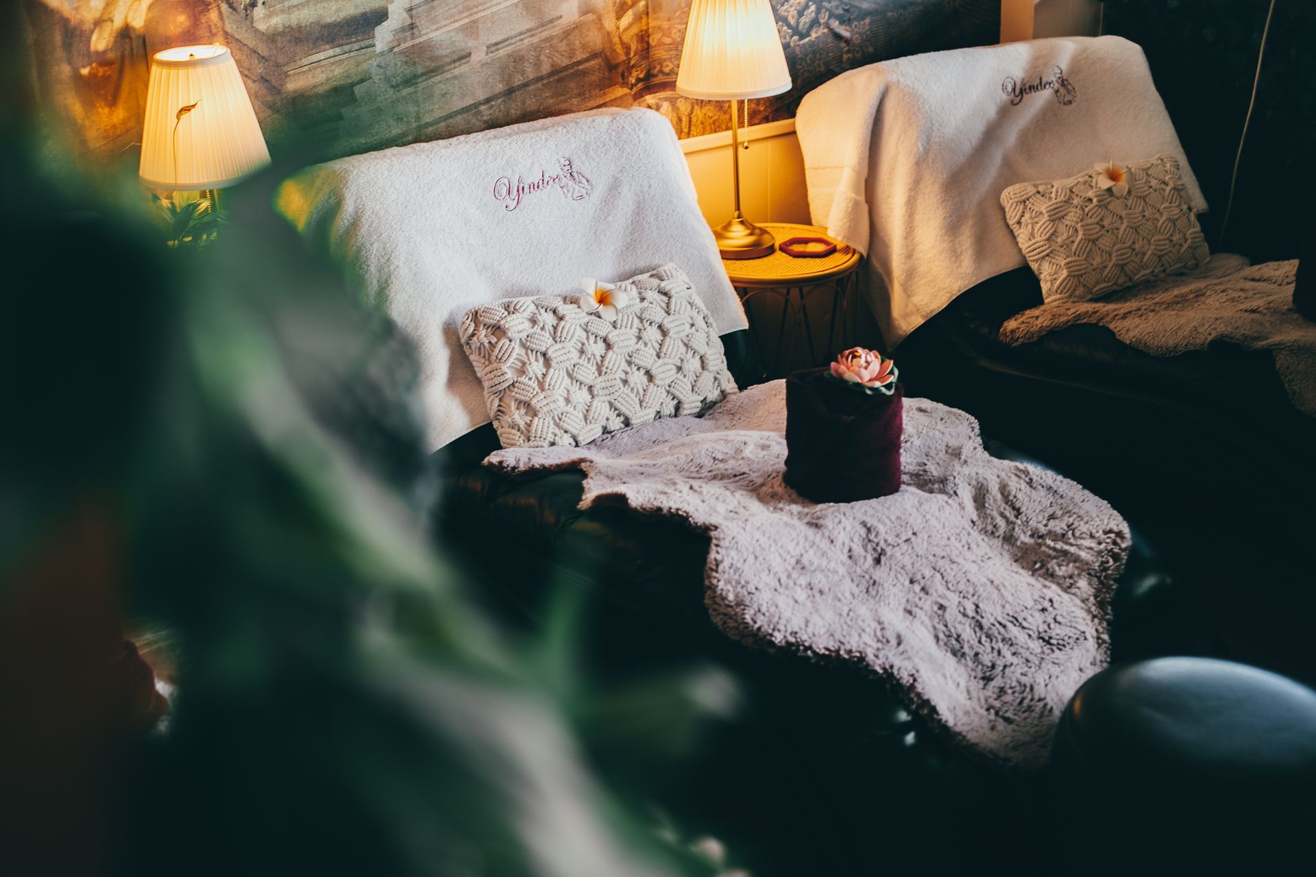 Cozy reading nook with two armchairs draped with white blankets, knitted pillows, and soft lighting.